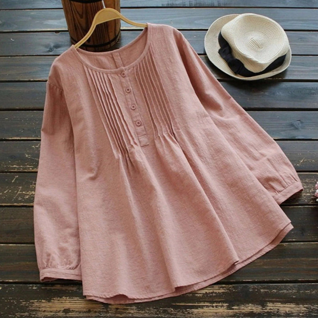 Pink dress on a wooden surface with a hat in the background